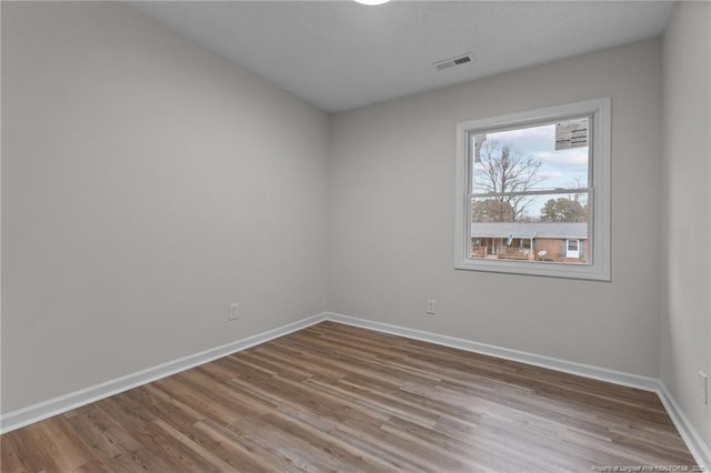 spare room featuring visible vents, wood finished floors, and baseboards