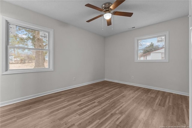 spare room with plenty of natural light, visible vents, light wood-type flooring, and baseboards