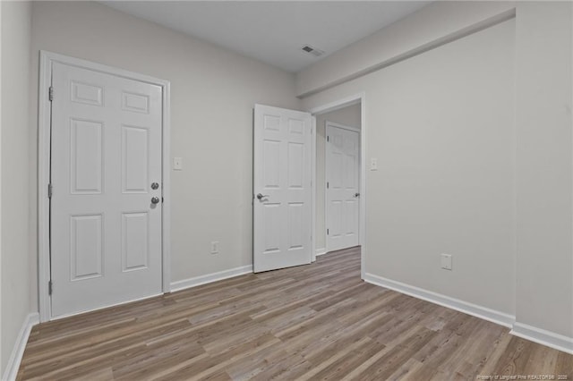 spare room with light wood-style flooring, visible vents, and baseboards