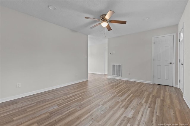 spare room with light wood-type flooring, visible vents, a textured ceiling, baseboards, and ceiling fan