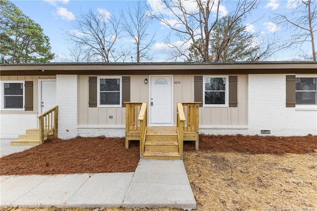 ranch-style house with entry steps, brick siding, board and batten siding, and crawl space