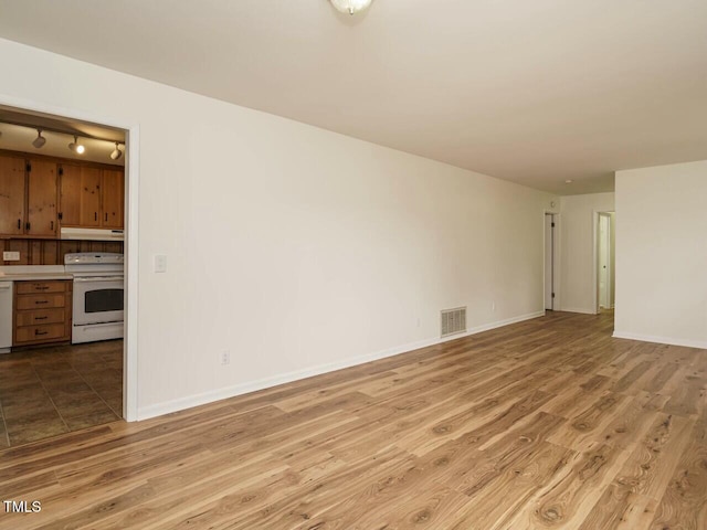 unfurnished living room with hardwood / wood-style flooring and rail lighting