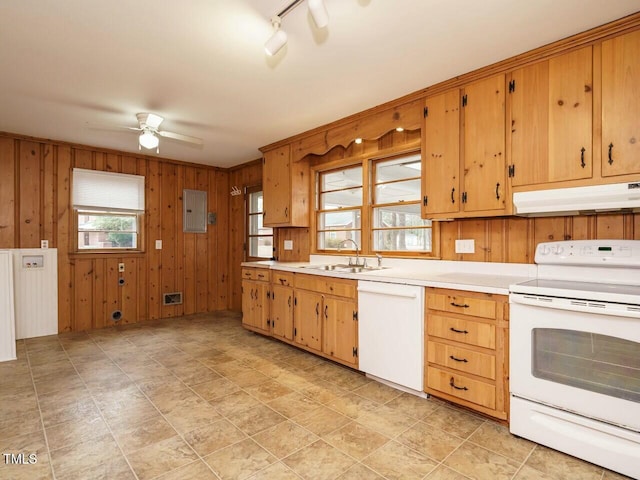 kitchen featuring wooden walls, sink, electric panel, ceiling fan, and white appliances