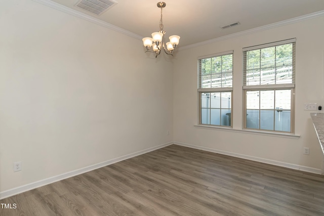 spare room with dark wood-type flooring, ornamental molding, and a chandelier