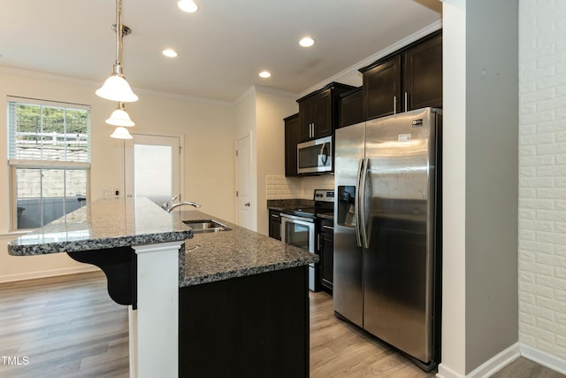 kitchen with sink, decorative light fixtures, stainless steel appliances, and a center island with sink