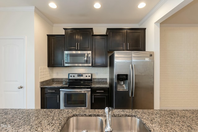 kitchen featuring sink, dark stone countertops, backsplash, ornamental molding, and stainless steel appliances