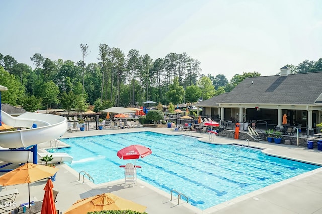 view of pool with a water slide and a patio area