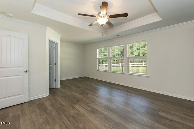 unfurnished room with crown molding, a tray ceiling, dark wood-type flooring, and ceiling fan