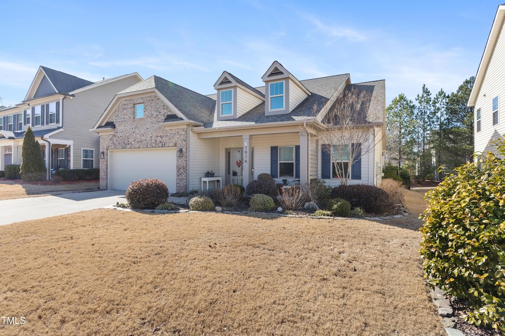 view of front of property with a porch, a garage, and a front lawn