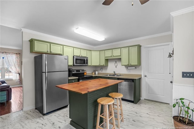 kitchen with green cabinetry, stainless steel appliances, wood counters, and sink