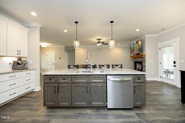 kitchen with pendant lighting, sink, white cabinetry, a fireplace, and stainless steel dishwasher