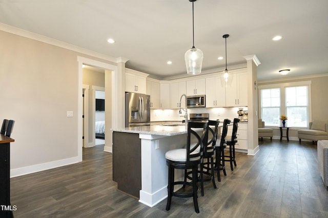 kitchen featuring crown molding, appliances with stainless steel finishes, white cabinetry, light stone countertops, and decorative light fixtures