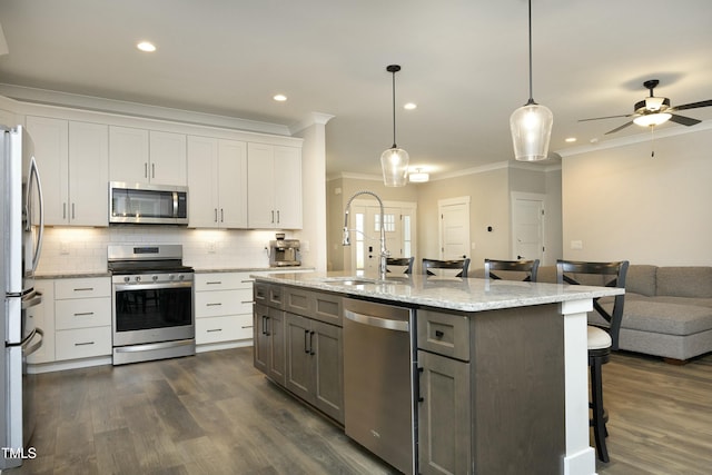 kitchen with white cabinetry, appliances with stainless steel finishes, a breakfast bar area, and pendant lighting