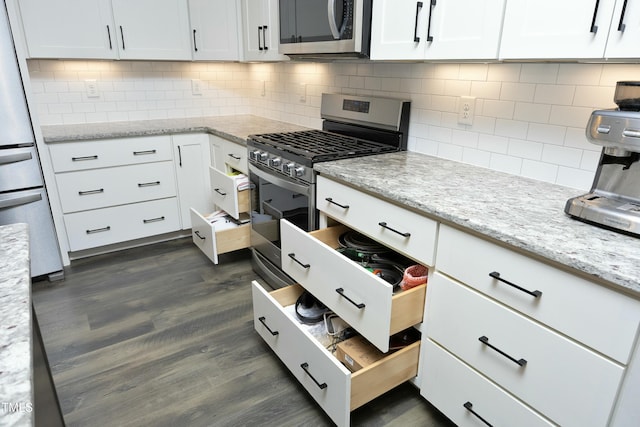 kitchen with white cabinetry, tasteful backsplash, dark hardwood / wood-style flooring, stainless steel appliances, and light stone countertops