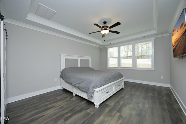 bedroom with dark hardwood / wood-style flooring, ornamental molding, ceiling fan, a raised ceiling, and a barn door