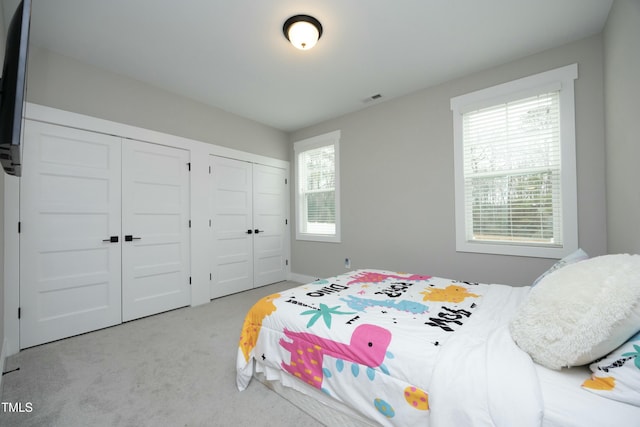 bedroom with multiple closets and light carpet