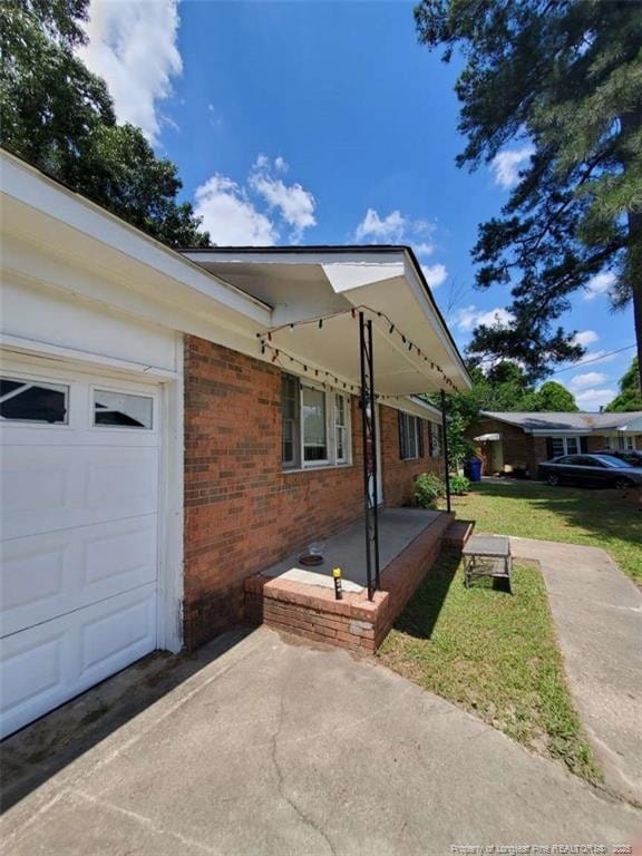 view of side of home featuring a garage and a lawn