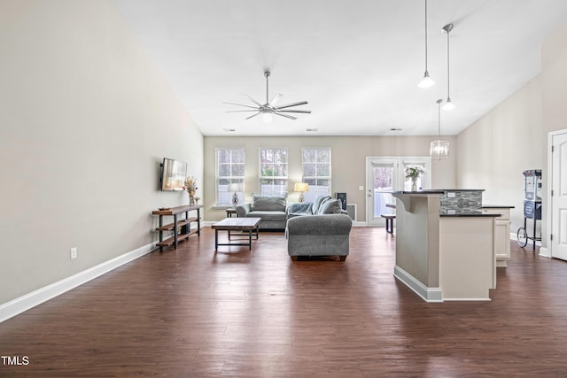 living room with baseboards, dark wood finished floors, and ceiling fan with notable chandelier