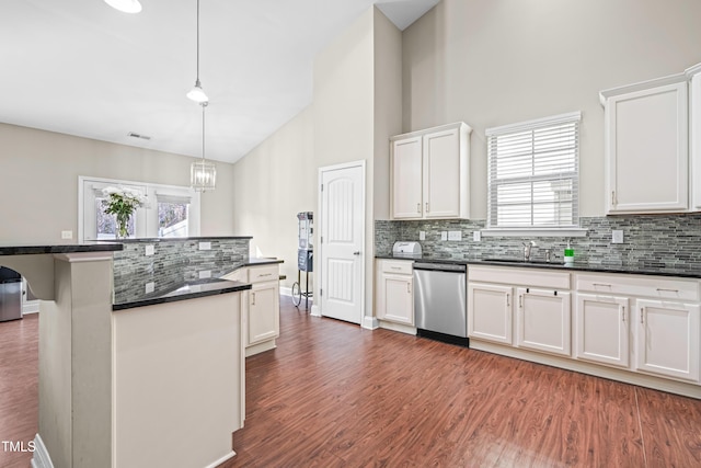 kitchen featuring wood finished floors, a sink, white cabinets, hanging light fixtures, and dishwasher