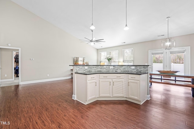 kitchen featuring high vaulted ceiling, ceiling fan with notable chandelier, white cabinets, hanging light fixtures, and dark wood finished floors