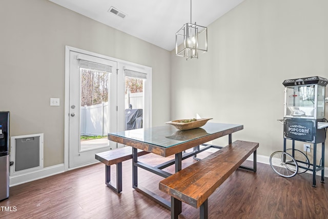 dining area featuring a notable chandelier, baseboards, visible vents, and wood finished floors