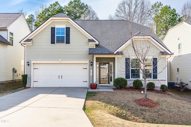 traditional home featuring a garage, concrete driveway, central AC unit, and roof with shingles