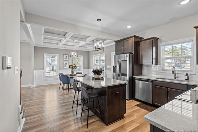 kitchen with dark brown cabinetry, sink, decorative light fixtures, a center island, and appliances with stainless steel finishes