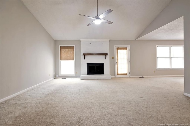 unfurnished living room featuring a brick fireplace, light carpet, lofted ceiling, and ceiling fan