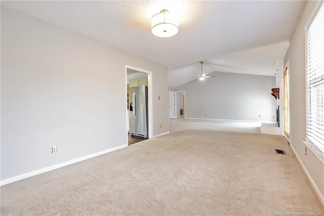 unfurnished room with lofted ceiling, ceiling fan, a wealth of natural light, a textured ceiling, and light carpet