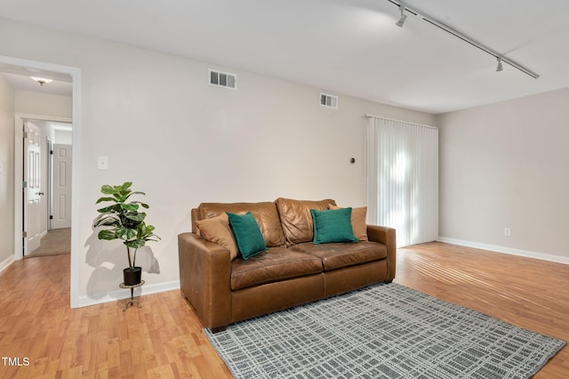 living room with rail lighting and light wood-type flooring