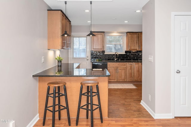 kitchen with pendant lighting, tasteful backsplash, dishwasher, a kitchen bar, and kitchen peninsula