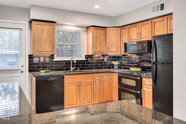 kitchen featuring dark stone counters, a wealth of natural light, sink, and black appliances