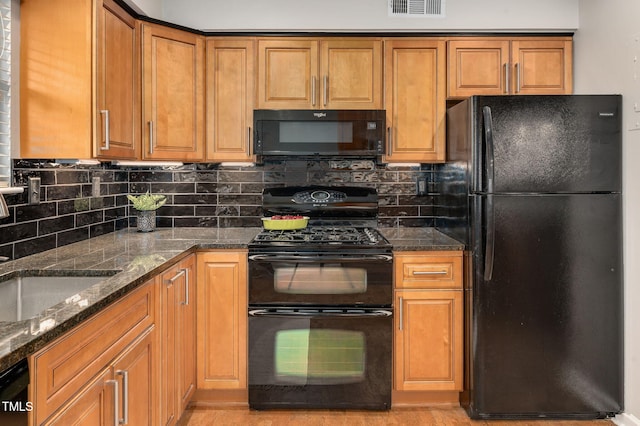 kitchen featuring tasteful backsplash, sink, dark stone counters, and black appliances