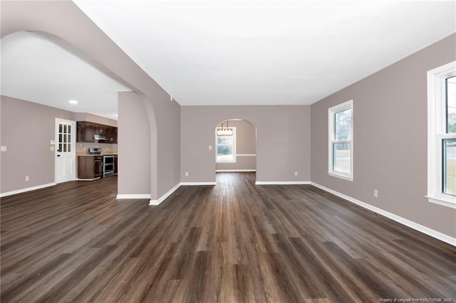 unfurnished living room featuring a healthy amount of sunlight and dark wood-type flooring