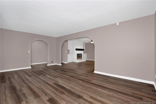 unfurnished living room featuring dark wood-type flooring and ceiling fan