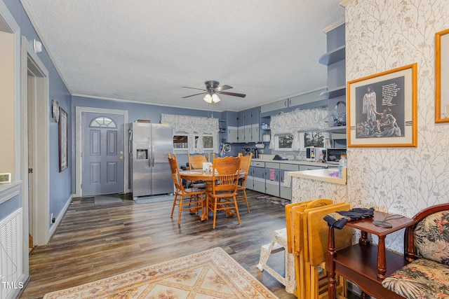 dining space with ceiling fan, dark wood-type flooring, and a textured ceiling