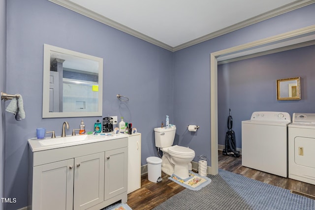 bathroom with hardwood / wood-style floors, ornamental molding, vanity, washing machine and clothes dryer, and toilet