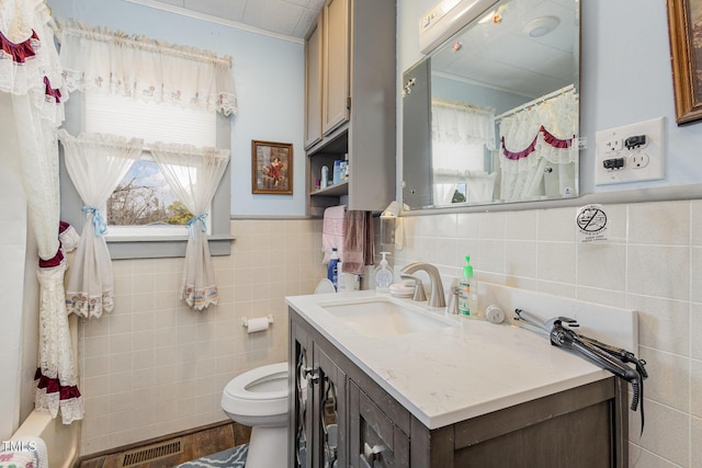 bathroom featuring ornamental molding, vanity, toilet, and tile walls