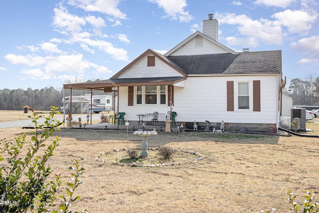 back of property featuring central AC unit, covered porch, and a lawn