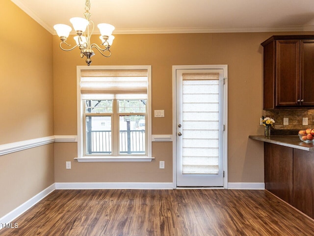 entryway featuring dark hardwood / wood-style flooring, crown molding, and an inviting chandelier