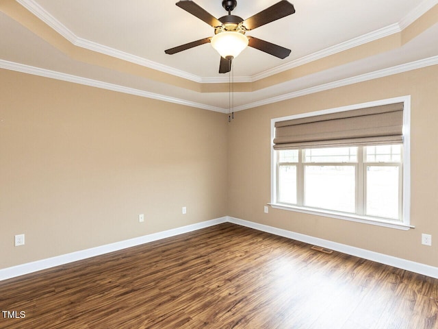 empty room featuring a raised ceiling, crown molding, hardwood / wood-style floors, and ceiling fan