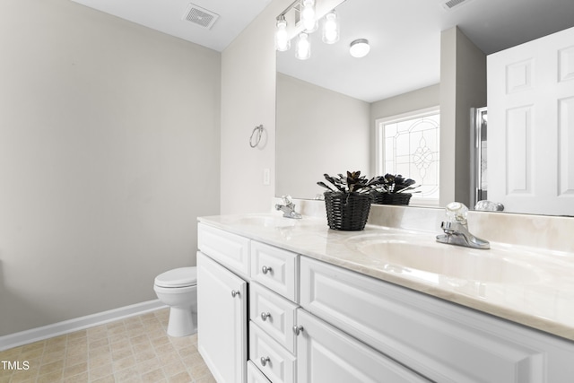 bathroom featuring double vanity, a sink, visible vents, and baseboards