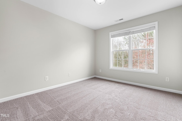 spare room with carpet flooring, visible vents, and baseboards