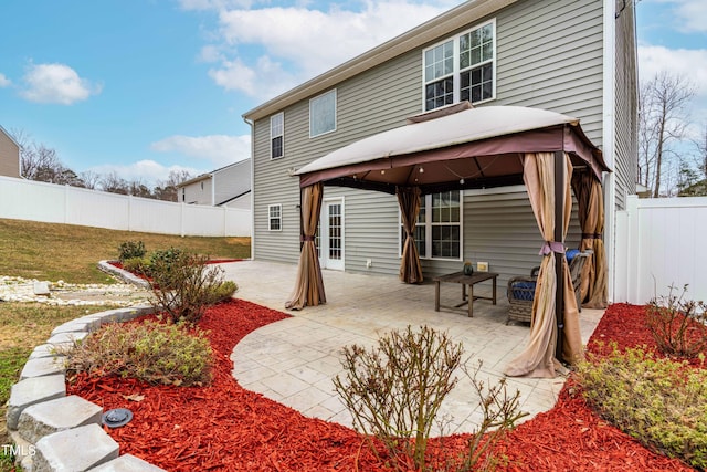 back of house featuring a patio area, a fenced backyard, a yard, and a gazebo