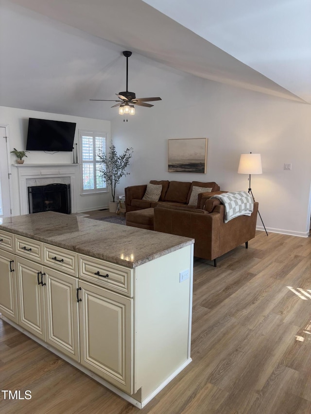 living room featuring ceiling fan, light hardwood / wood-style flooring, and lofted ceiling