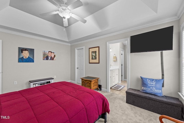 bedroom featuring a tray ceiling, crown molding, light colored carpet, ensuite bathroom, and ceiling fan