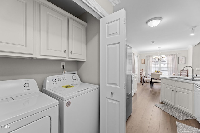 laundry area featuring separate washer and dryer, wood finished floors, a sink, ornamental molding, and an inviting chandelier