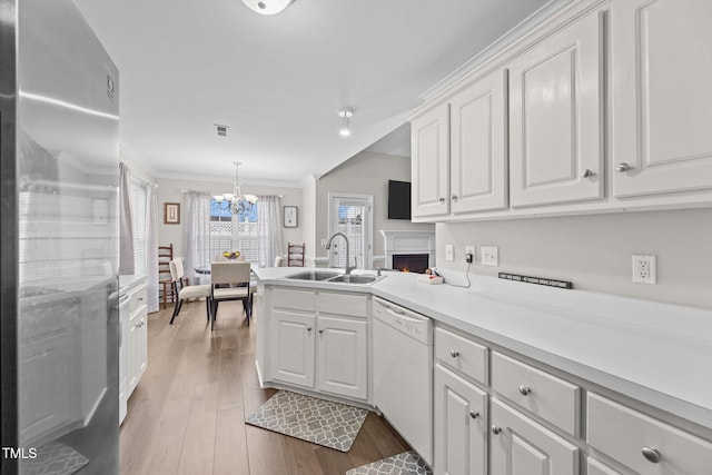 kitchen featuring light countertops, white cabinets, a sink, dishwasher, and stainless steel refrigerator