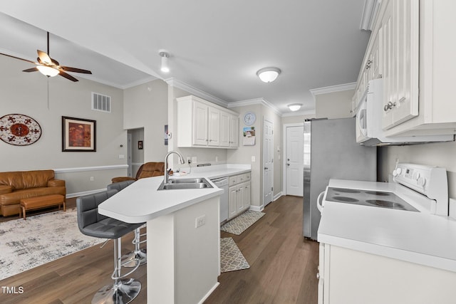 kitchen featuring light countertops, visible vents, a sink, white appliances, and a kitchen breakfast bar