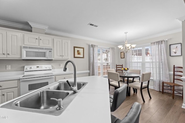 kitchen featuring pendant lighting, light countertops, visible vents, white cabinets, and white appliances